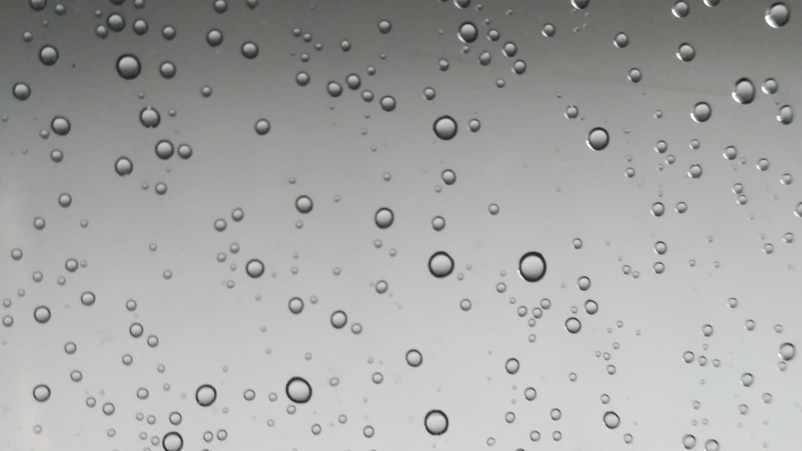 Close-up of small water droplets on smooth glass, which leave mineral spots as they dry in Los Angeles