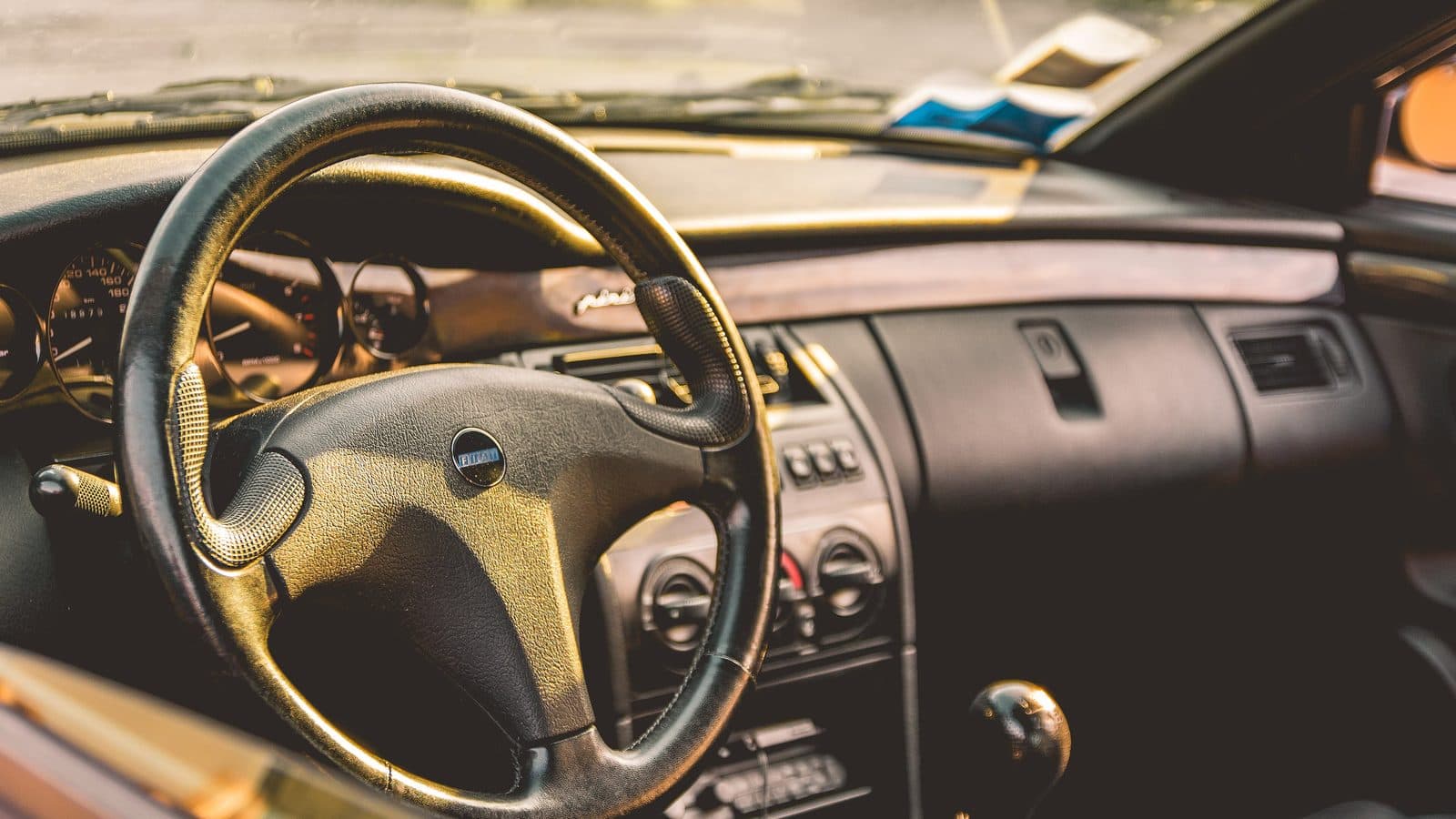 Car dashboard, steering wheel and gear shifter in bright daylight