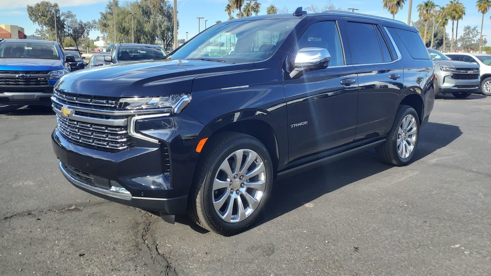 Clean, glossy navy Chevrolet Tahoe SUV parked under a blue sky with palm trees