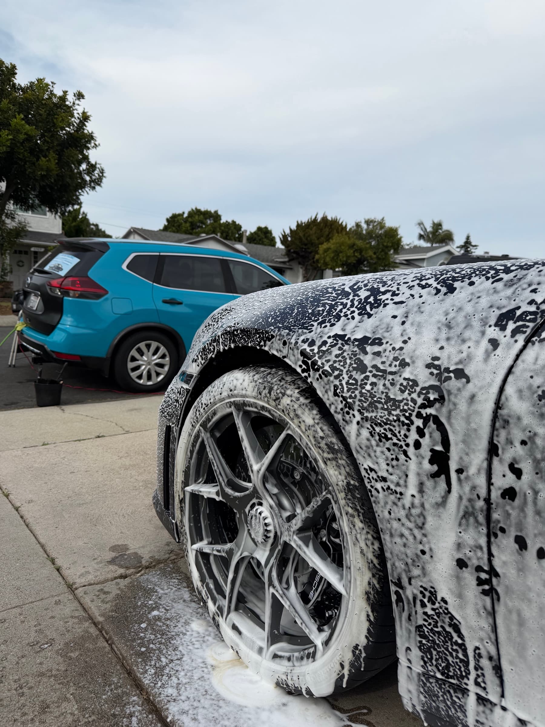 Close-up of a foam-covered wheel and fender during the pre-wash stage