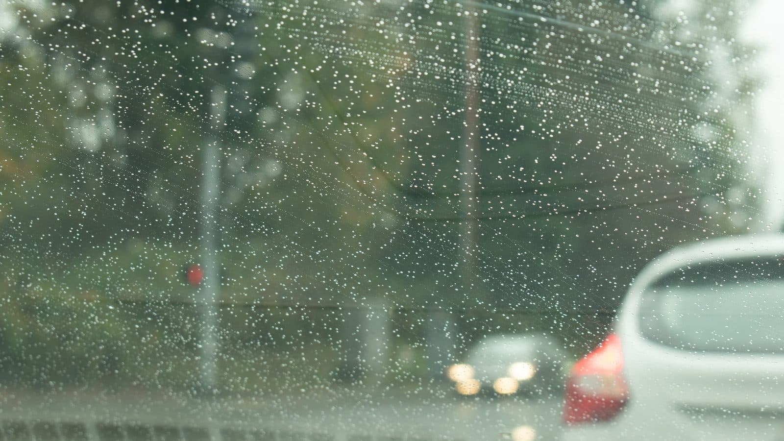 LA's first rain of the season — raindrops on the windshield Raindrops on a car windshield with blurred traffic and taillights ahead on a gray day