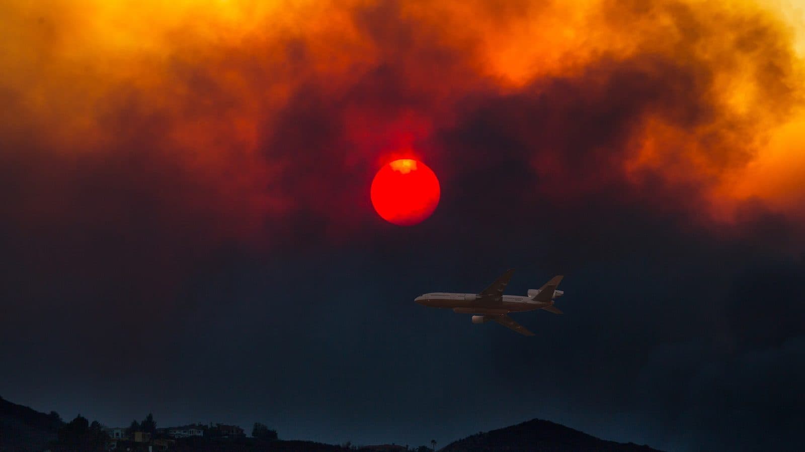 Wildfire smoke and ash in Southern California An air tanker flying under a red sun in thick wildfire smoke during the Woolsey Fire in Southern California