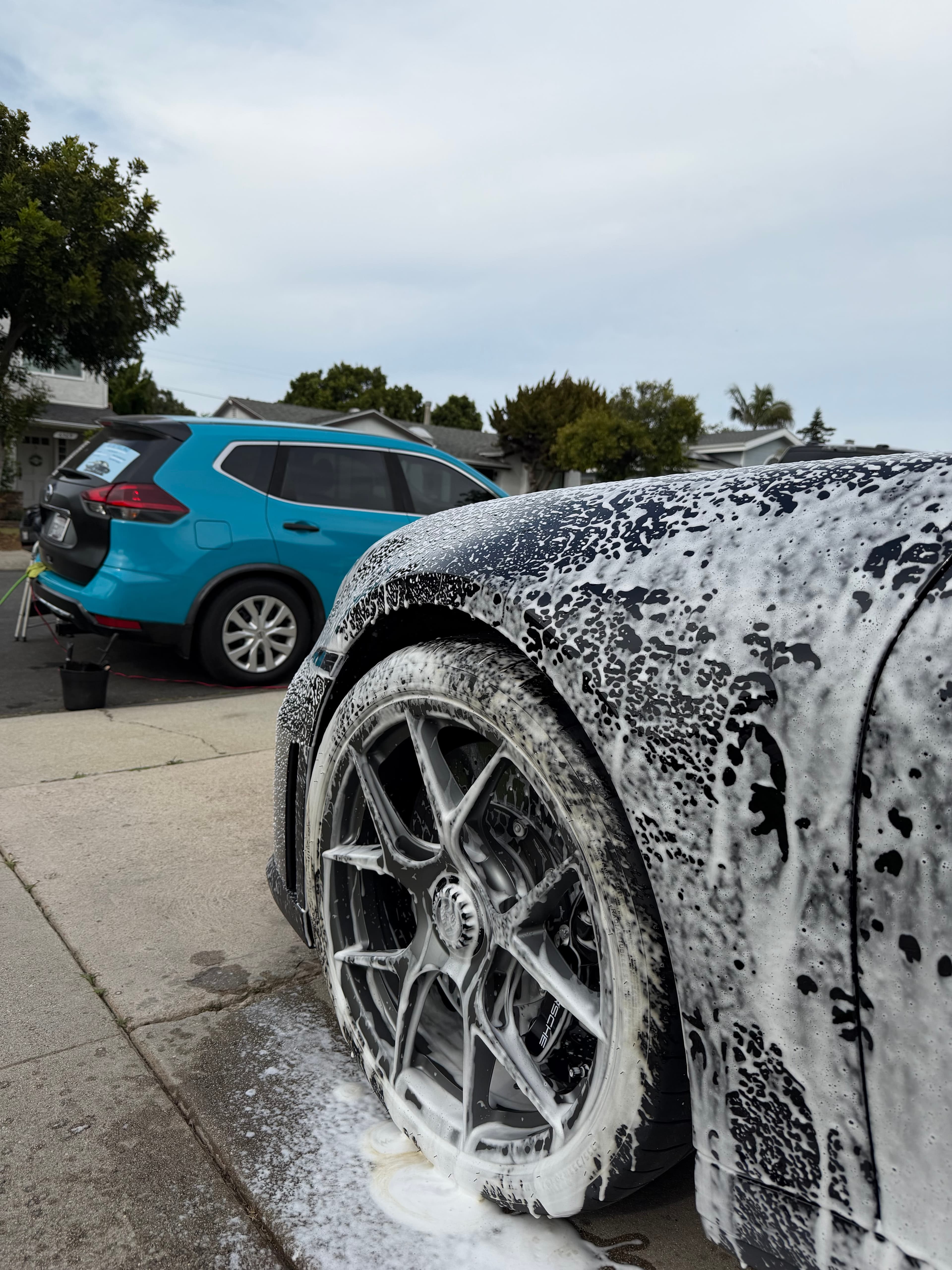 Close-up of a foam-covered wheel and fender during the pre-wash stage